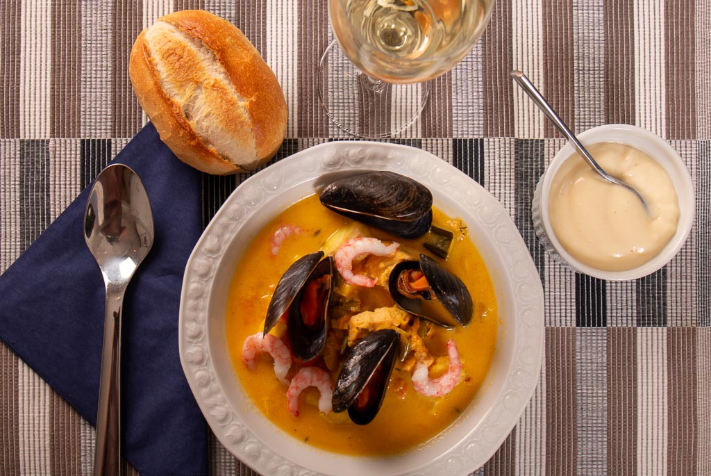 Saffransdoftande fisk och skaldjursgryta serverad med aioli, bröd och vitt vin
